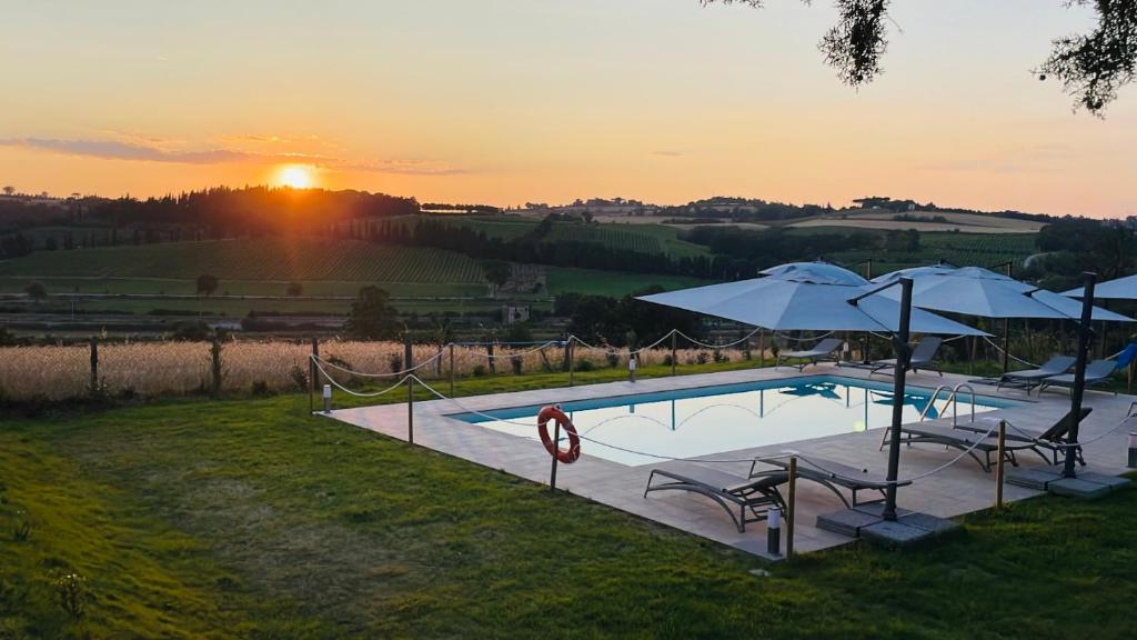 帕西亚诺Agriturismo con cucina Il Favaio的一个带遮阳伞和椅子的游泳池,享有日落美景