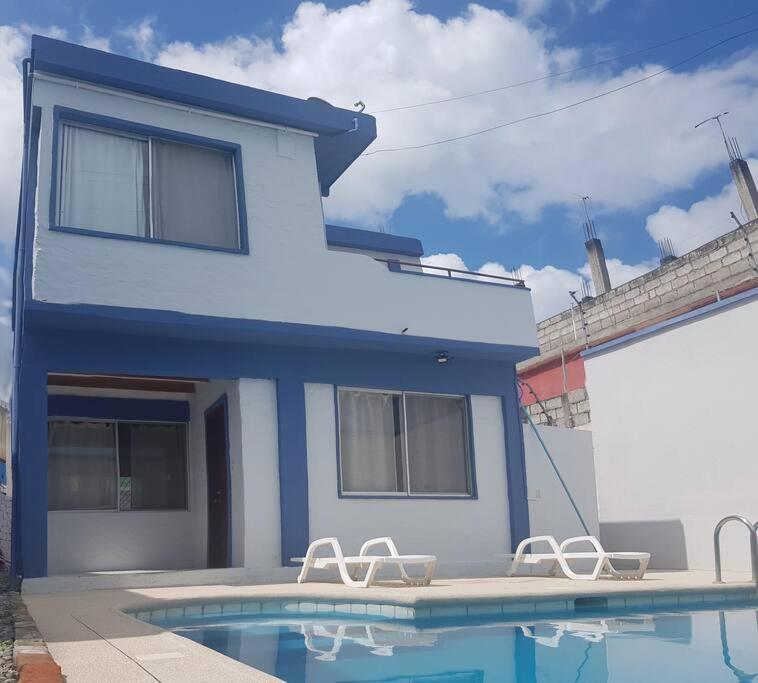 通苏帕Amplia casa en Tonsupa con piscina privada y WIFI的蓝色的房子,设有游泳池和两把椅子