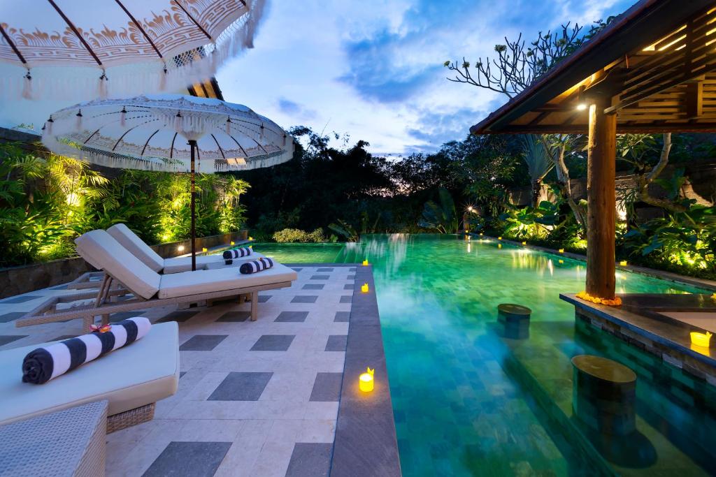坎古Adepa Resort的度假村的游泳池配有躺椅和遮阳伞
