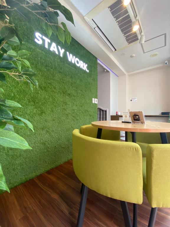 东京ステイワーク錦糸町的办公室,带绿色的墙壁,配有桌子和黄色的椅子