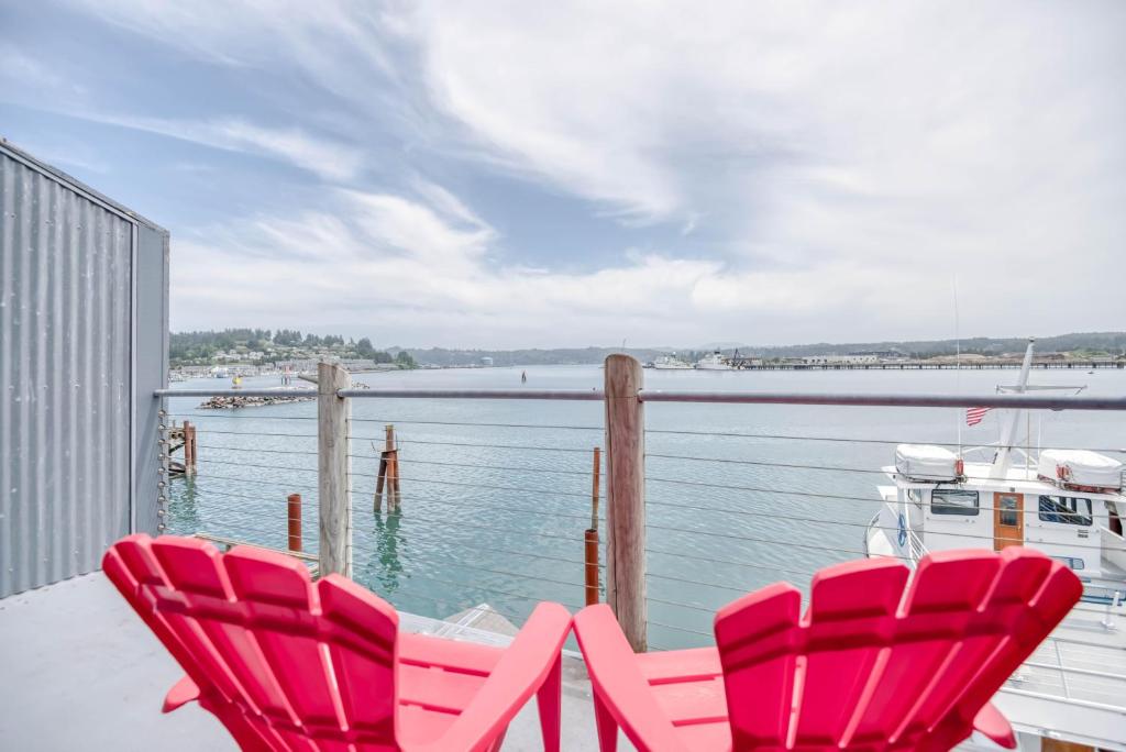 新港Ocean's Edge - Anchor Pier Lodge的两把红色椅子坐在一个俯瞰着水体的阳台