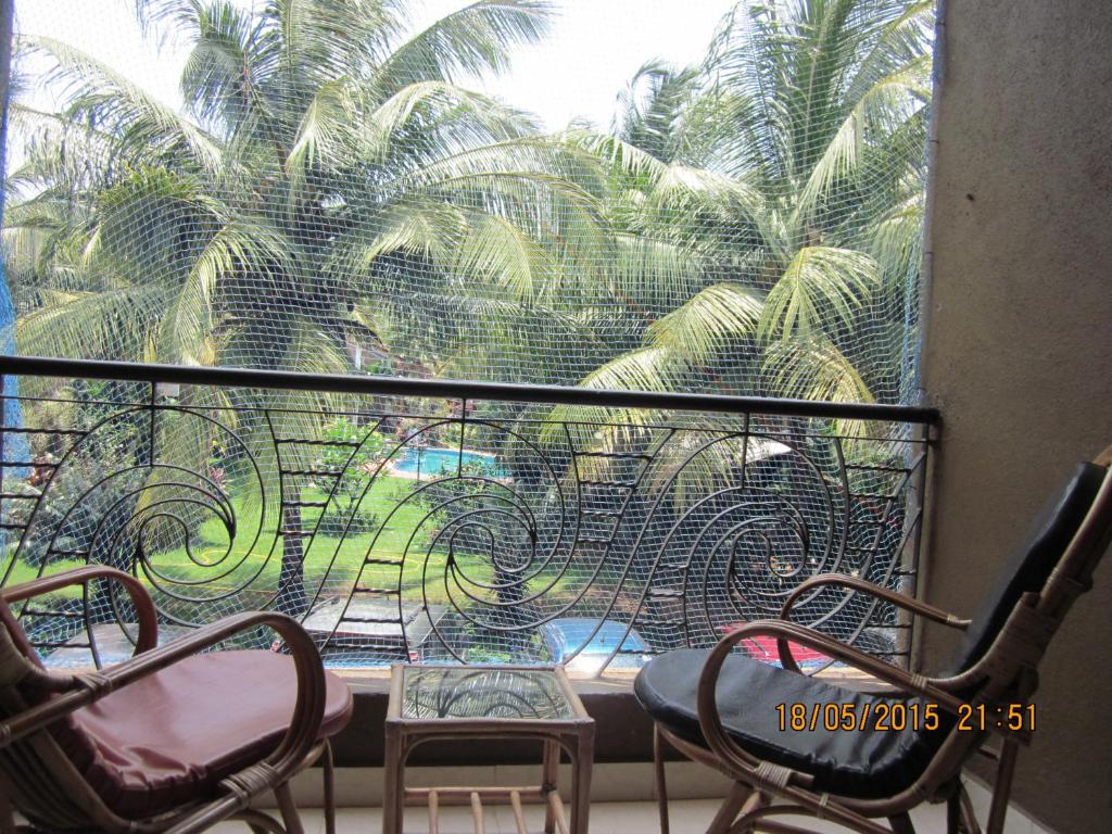 坎多林Apartment Du-2 Candolim的阳台配有两把椅子,窗户种有棕榈树。