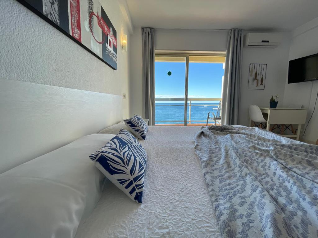 阿尔姆尼卡Apartahotel CHINASOL con Parking y Desayuno的一间卧室设有一张床,享有海景