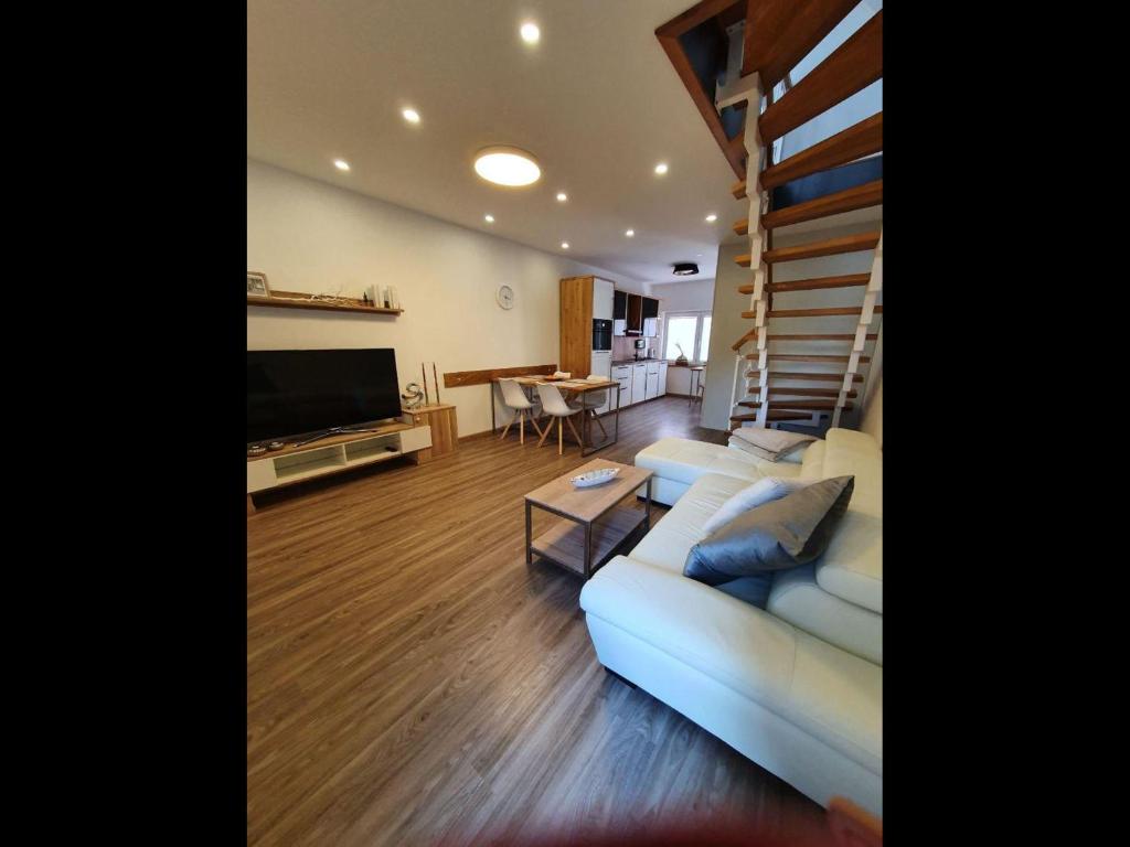胡苏姆NEU! Ferienhaus 54 Husum inkl Sauna的客厅设有白色沙发和楼梯。