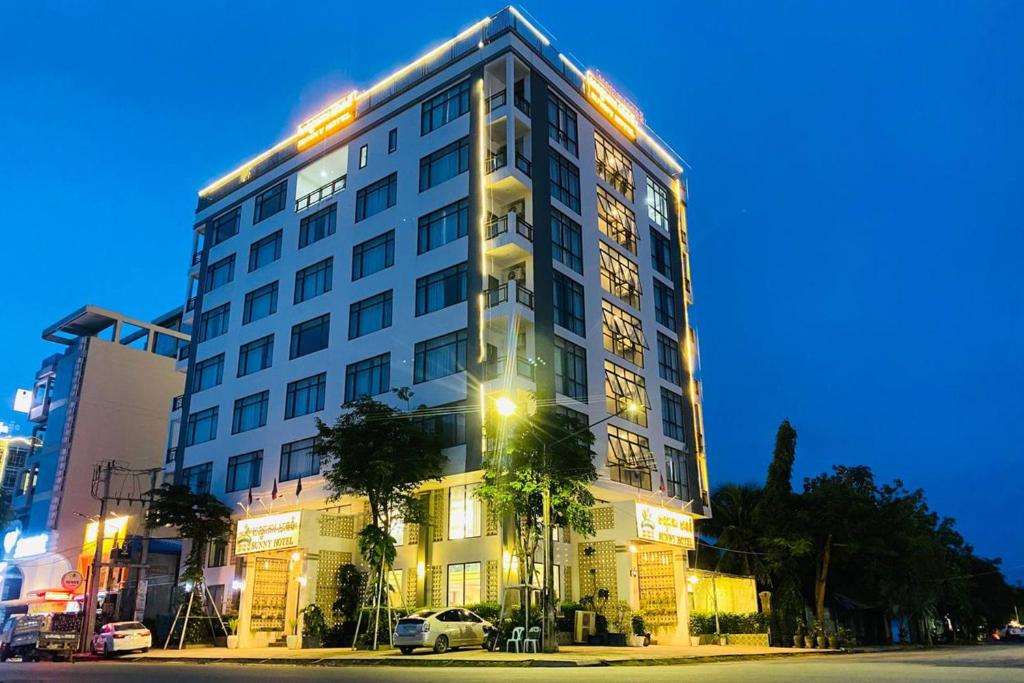 贡布Kampot Sunny Hotel的一座高大的白色建筑,上面有灯