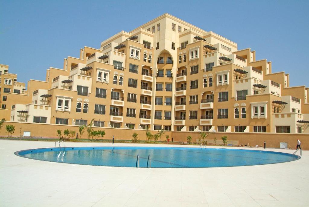 拉斯阿尔卡麦Hala Holiday Homes- Bab Al Bahr Residence, Al Marjan Island的一座大型建筑,前面设有一个游泳池