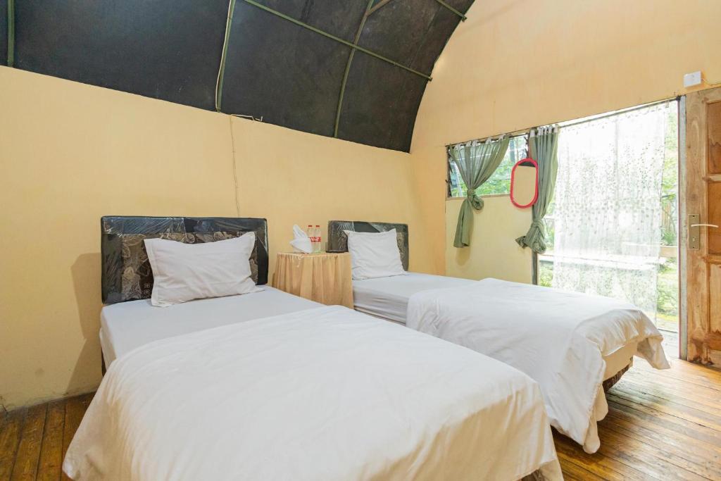 JunggoChikar Glamping At Wisata Coban Talun Mitra RedDoorz的一间卧室设有两张带白色床单的床和窗户。