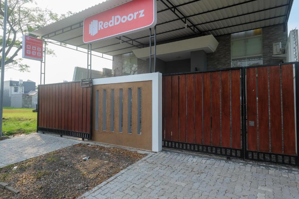 Kalibanteng-kidulRedDoorz near Kawasan Bandara Ahmad Yani Semarang 2的一座有红色门和标志的建筑