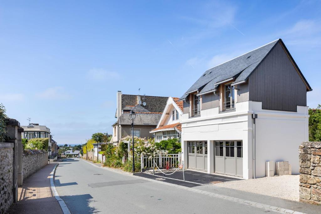 滨海圣布里阿克La Fleur du Moulin - Charmante maison avec jardin proche plage的街上有黑屋顶的白色房子