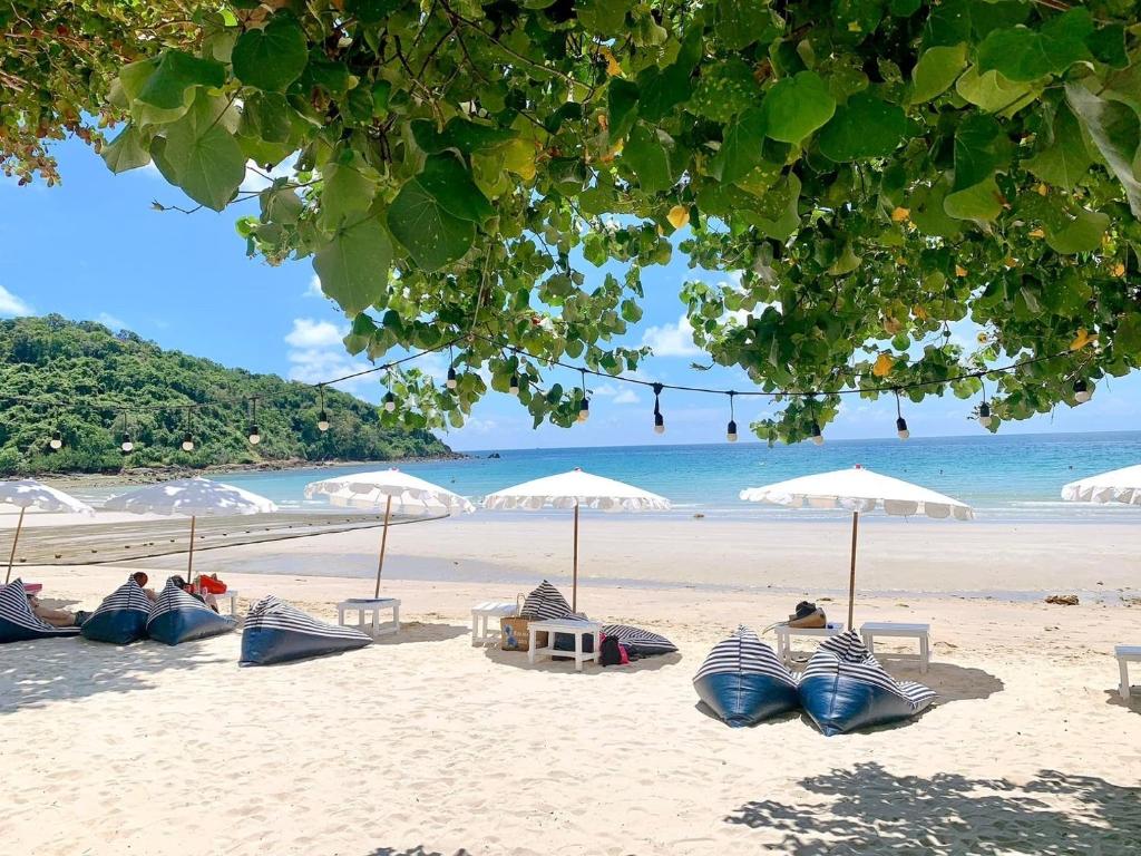 沙美岛Kerala Coco Resort的沙滩上,有遮阳伞,有人坐在沙滩上