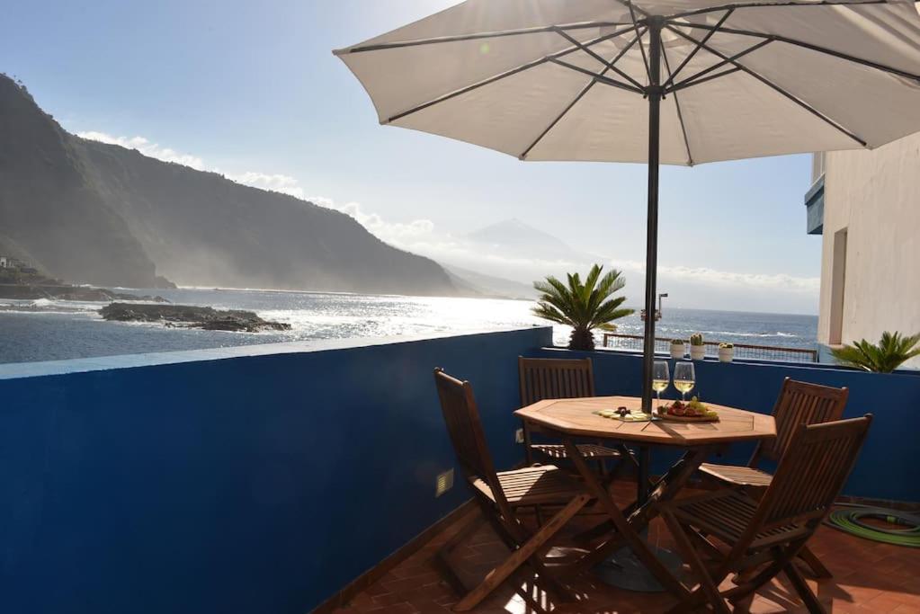 圣克鲁斯-德特内里费Beachfront Apartment - Tacoronte的一张桌子和椅子,配有雨伞和大海