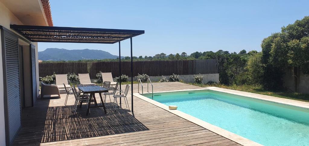 菲加里Villa au cœur du maquis的游泳池旁带桌椅的天井