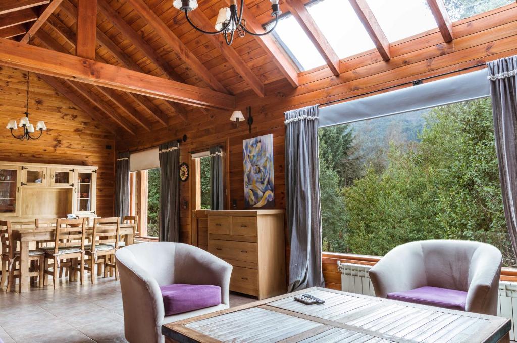 拉安戈斯图拉镇BOG Melania - casa en el bosque的客厅配有桌椅和大窗户
