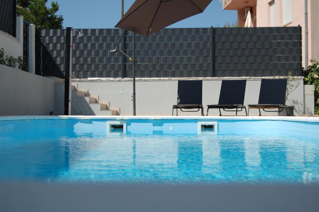 希杰弗朗吉卡NELA & SARA with heated swimming pool的一个带两把椅子和遮阳伞的游泳池