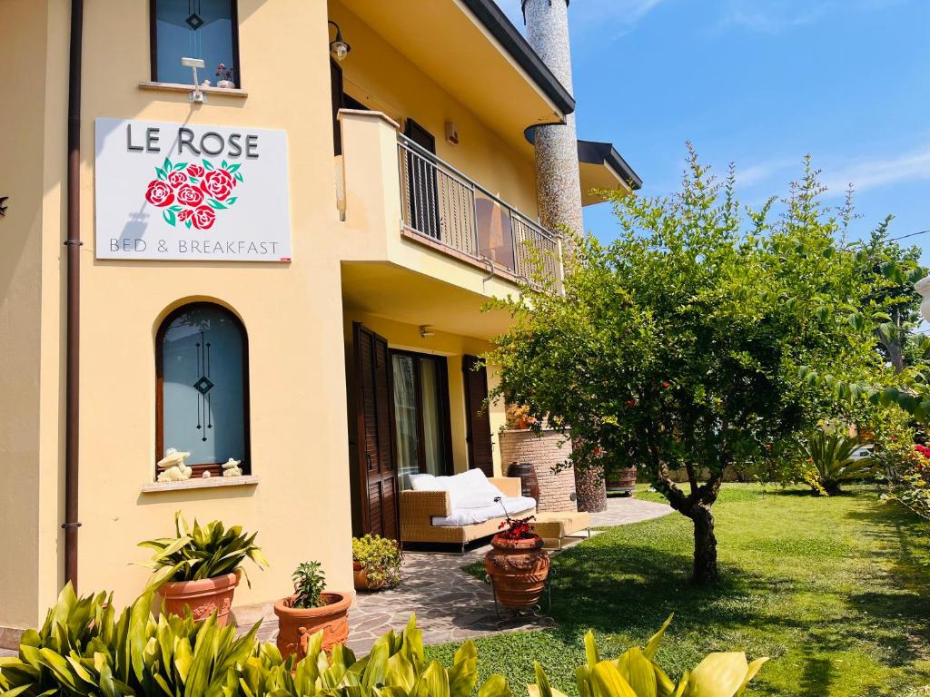 米萨诺阿德里亚蒂科Villa Le Rose - 5 minuti dal mare e Misano World Circuit的一座有玫瑰花标志的房子和一座花园