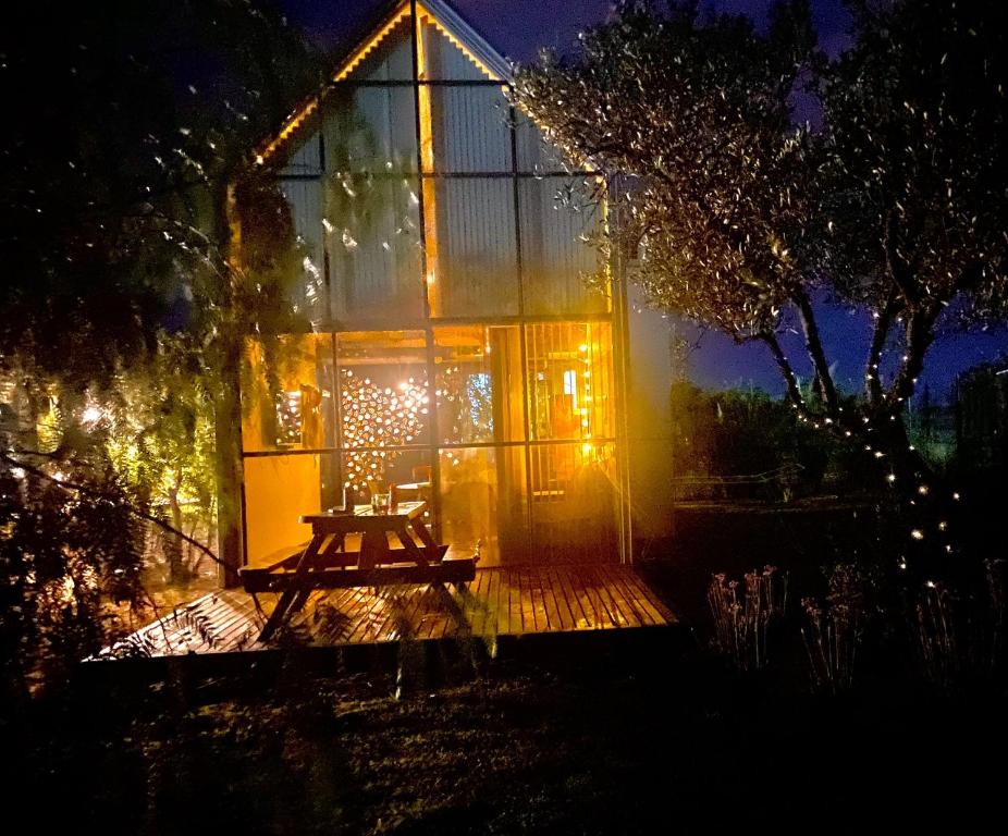 圣拉斐尔Finca La Escondida San Rafael的一间玻璃房子,晚上在房子前面设有野餐桌