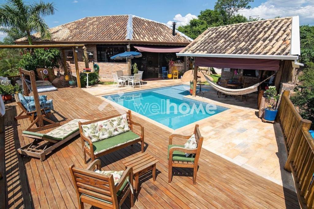 伊图佩瓦Casa na rocha com uma vista deslumbrante的房屋旁的游泳池设有椅子和吊床