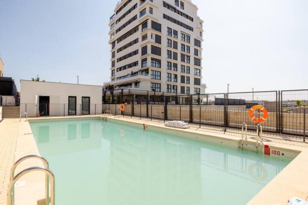 马德里Piso climatizado y parking的一座大型游泳池,其背后是一座高大的建筑