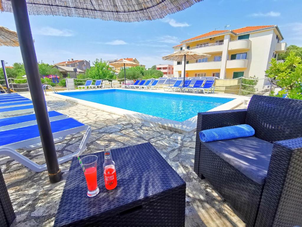 罗戈兹尼察Apartments CVITA HOLIDAY - Villa NATALI的游泳池畔的桌子上放着两杯饮料