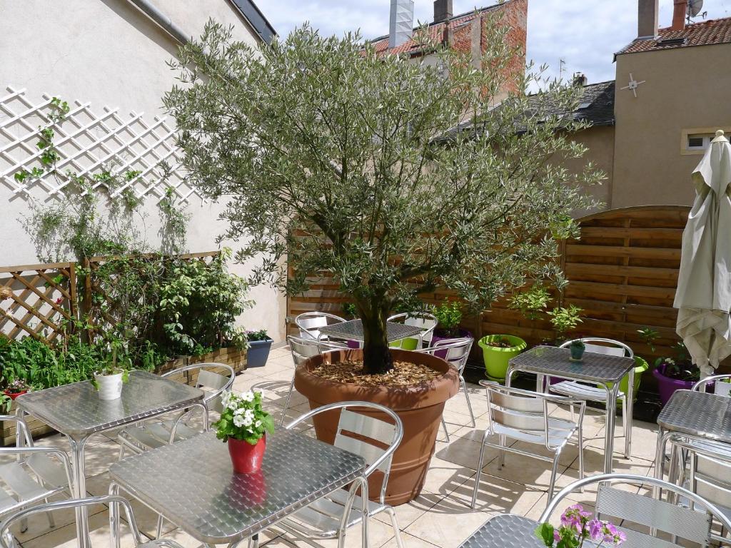 泰昂维Logis-Hôtel des Oliviers的庭院配有桌椅和一棵树