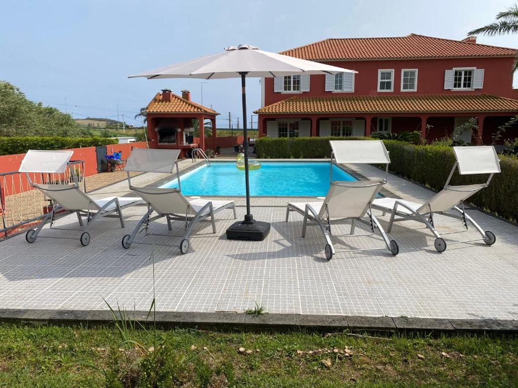 拉戈阿A Casa do Comandante的一组椅子和一把遮阳伞,位于游泳池旁