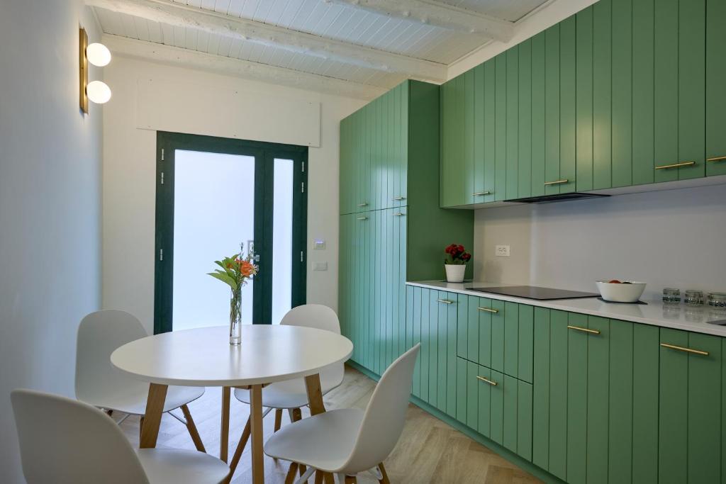 卡梅拉诺CAMERANOAPARTMENTS - L'ANGOLO DELLA PIAZZA的厨房配有绿色橱柜和桌椅
