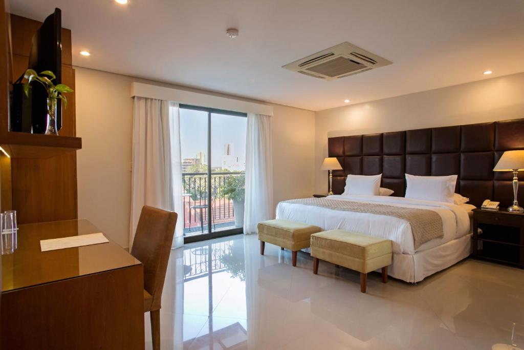亚松森拉斯洛马斯卡萨酒店的一间卧室配有一张床、一张书桌和一个窗户。