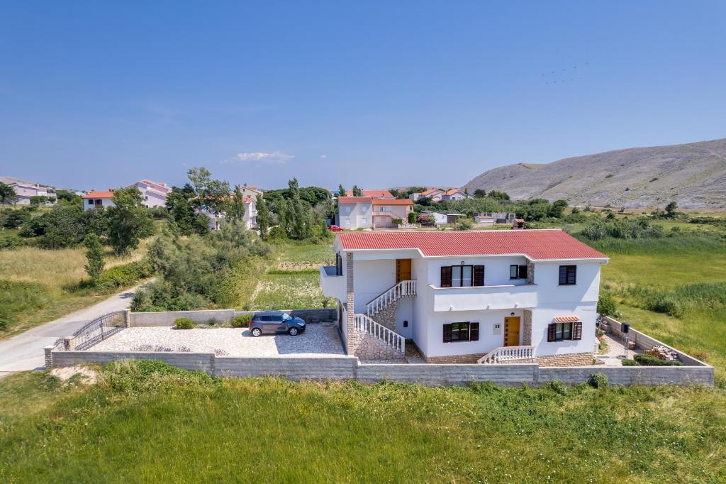 维拉斯奇Apartments Anica - Vlašići Island Pag的一座白色的房子,有一辆汽车停在田野里