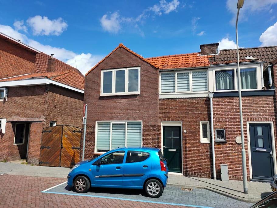 贝弗韦克Nice House with a garden in the centre near the sea and Amsterdam的停在砖房前的蓝色汽车