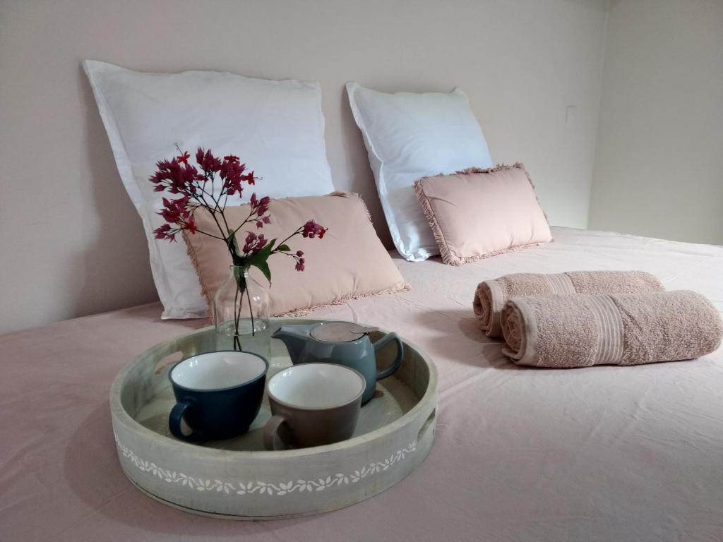帕皮提Chalet Ohana, airport family house的床上的带杯子的托盘和花瓶