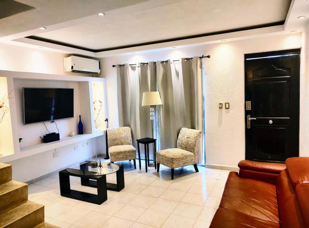 坎昆Casa de Cielo y Mar en Cancún的客厅配有沙发、椅子和电视