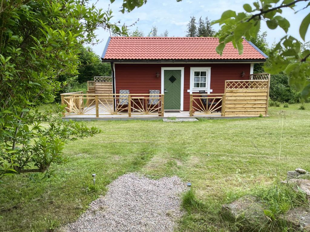 费尔耶斯塔登Newly built cozy cottage on the east side of Öland的一座红色的房子,设有甲板和庭院
