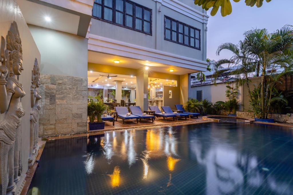 暹粒Siem Reap Comforts Hostel的一座游泳池,位于一座带蓝色椅子的建筑的中间