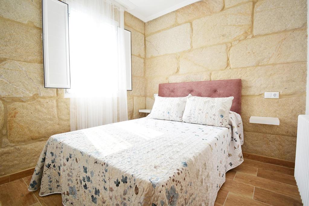 庞特维德拉Casa con jardín en Pontevedra的石墙客房的卧室配有一张床