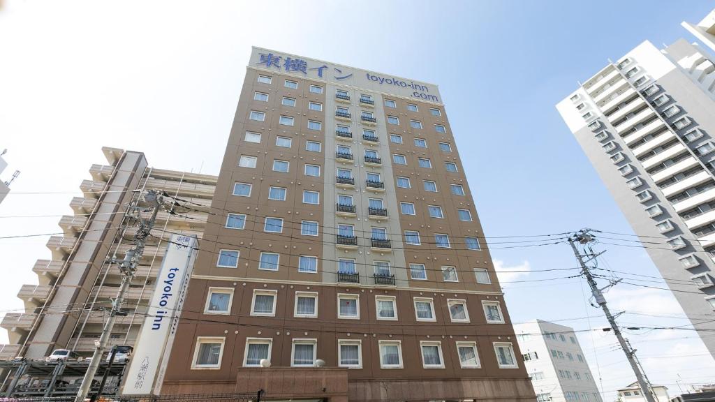 八潮市Toyoko Inn Yashio Ekimae的两栋建筑中间的高楼