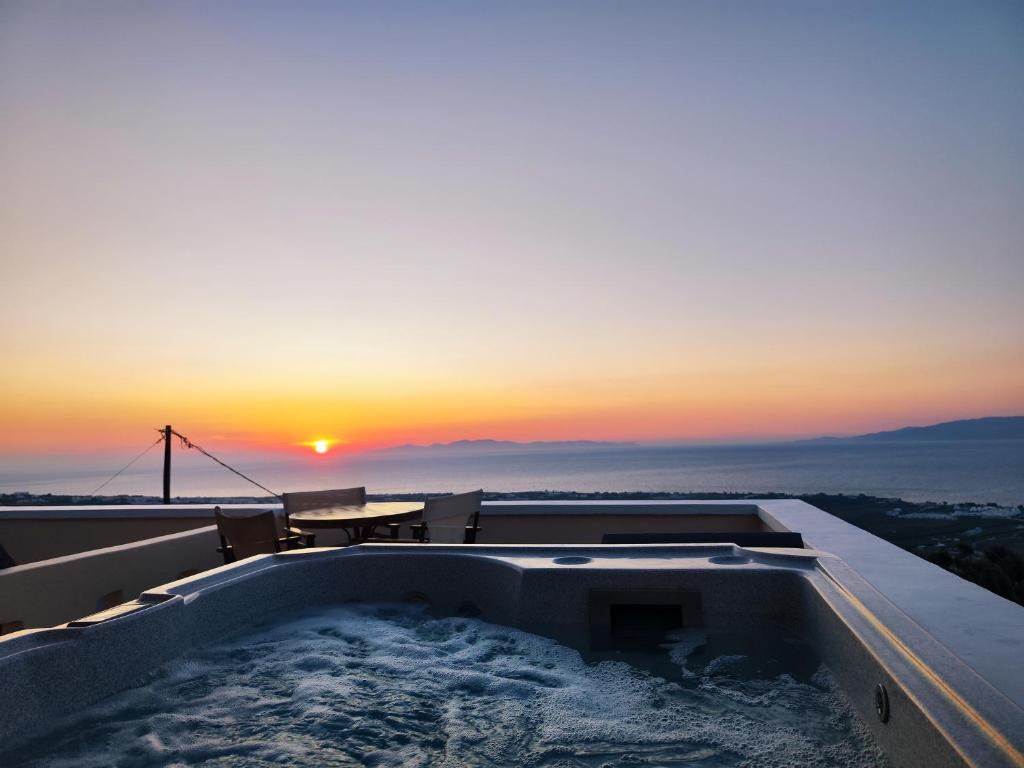伊亚Panorama Oia Apartments的屋顶上的热水浴池,享有日落美景
