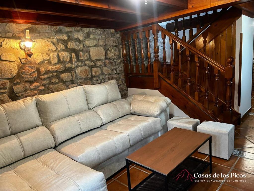 RuenesVivienda vacacional El Cau - Casas de Los Picos的带沙发和石墙的客厅