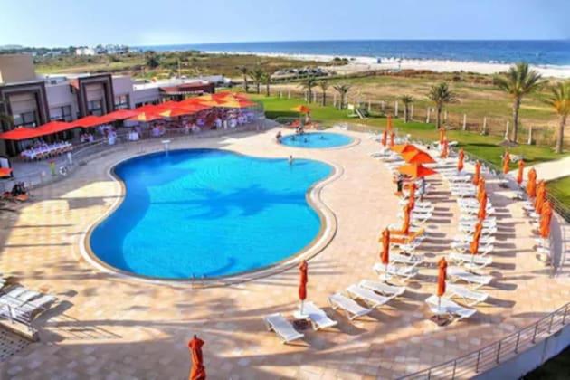 比塞大Andalucia Bizerte plage et piscine的享有带椅子和遮阳伞的游泳池的景色