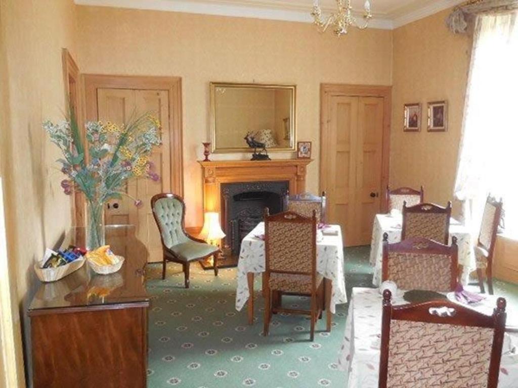 阿伯丁Butlers Guest House的客厅配有桌椅和壁炉