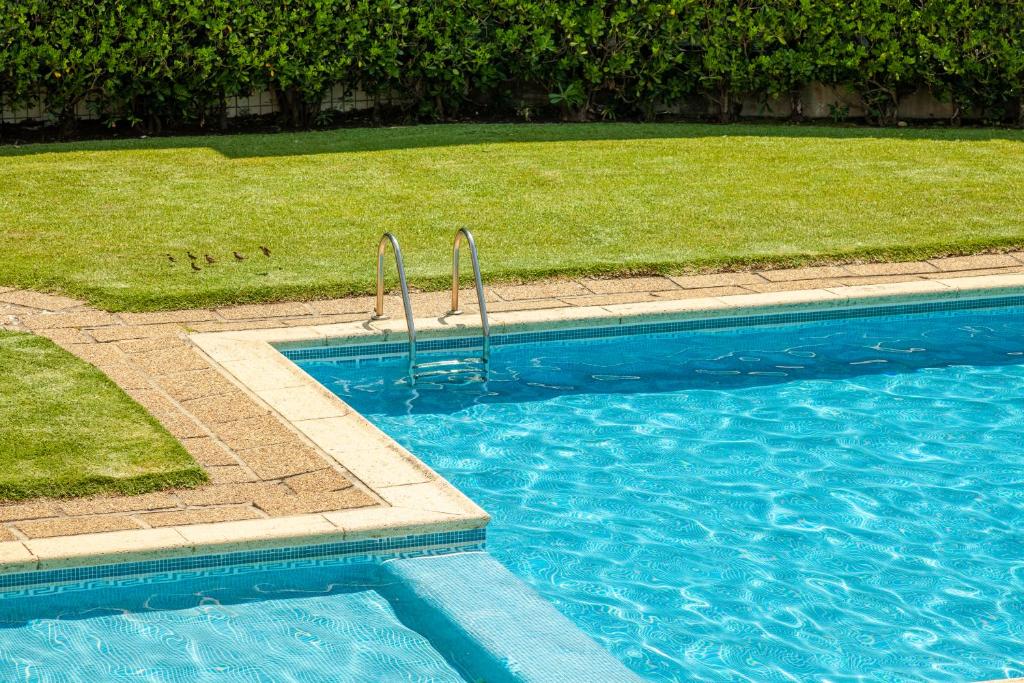 埃斯波森迪Apartamento Bela Vista - Minho's Guest的蓝色的游泳池旁设有草地