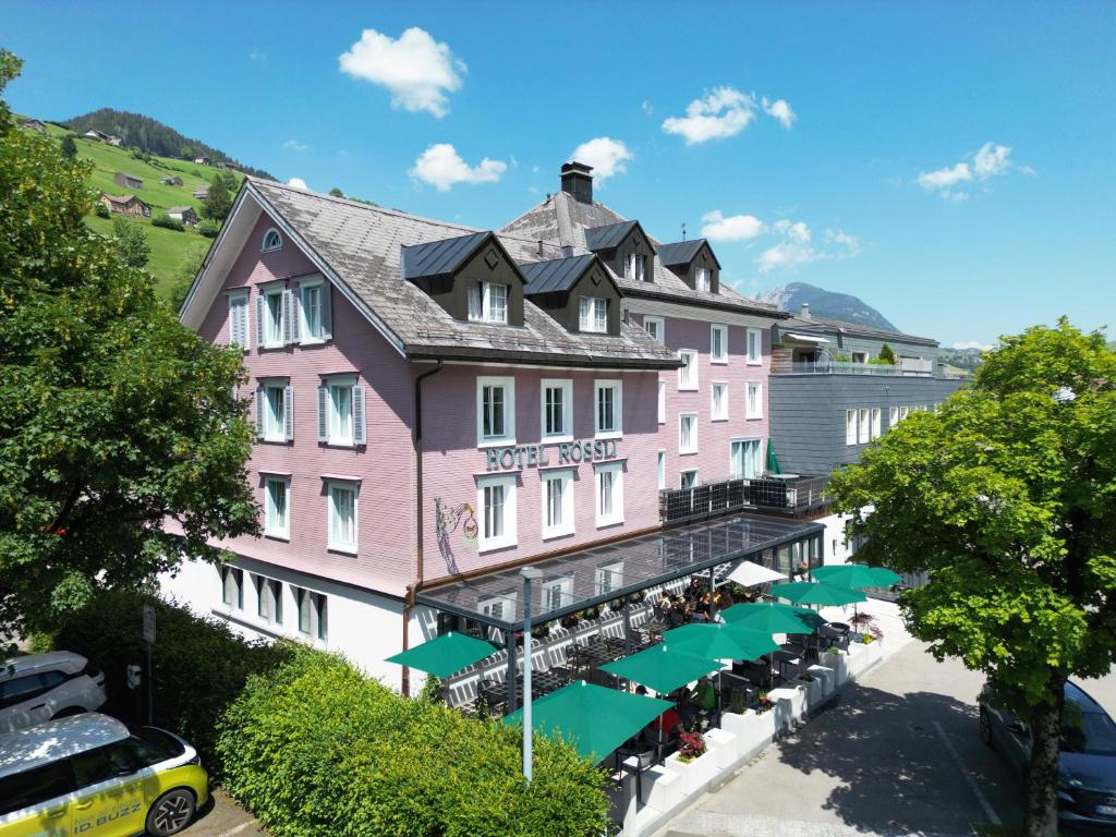 Alt Sankt Johann洛斯里酒店餐厅的前面有绿伞的粉红色建筑