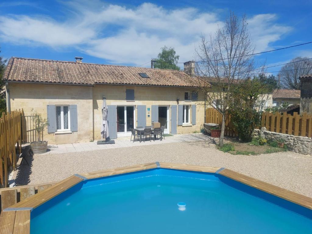 Saint-Magne-de-CastillonL Escale des Vignes GITE proche Saint Emilion Chateau Beynat的前面有一个蓝色游泳池的房子