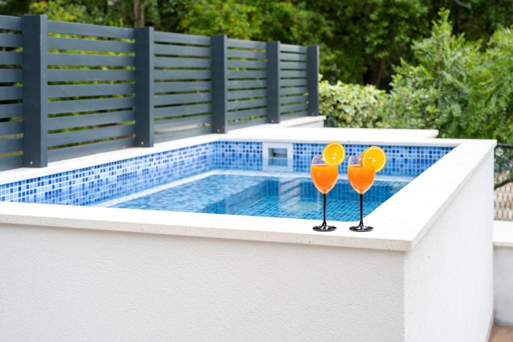 奥米什Holiday Home Greystone的两把橘子眼镜坐在游泳池旁