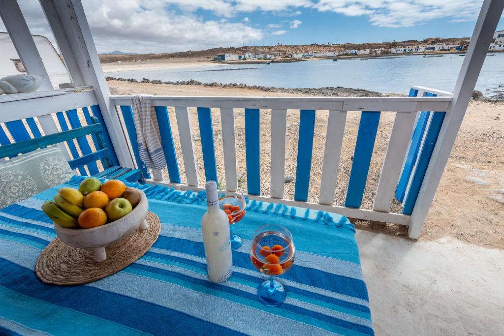 MajanichoCabin in front of idyllic majanicho beach的一张桌子,上面放着一碗水果和一瓶葡萄酒