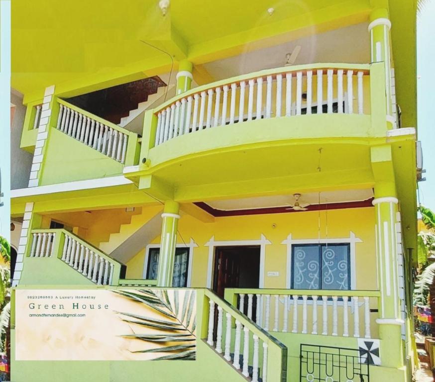 曼德姆Green House Stay的黄色房子的一侧设有阳台
