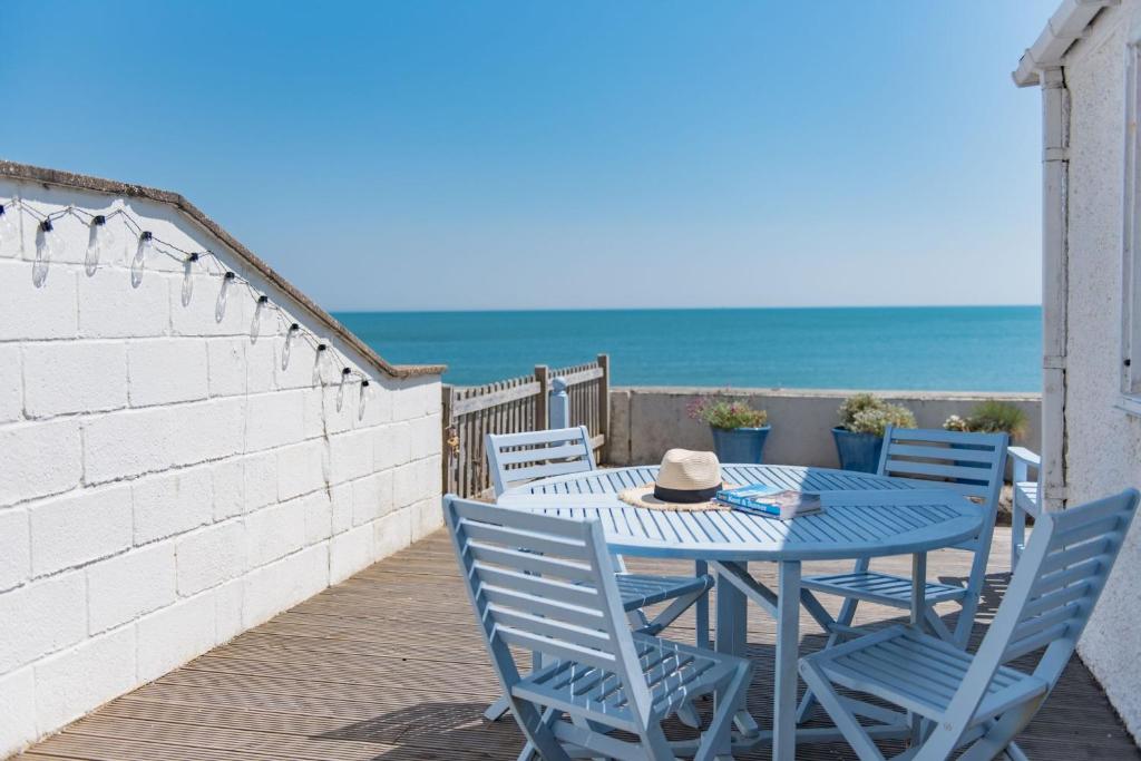 桑盖特Wave Cottage by Bloom Stays的海滩甲板上的蓝色桌子和椅子