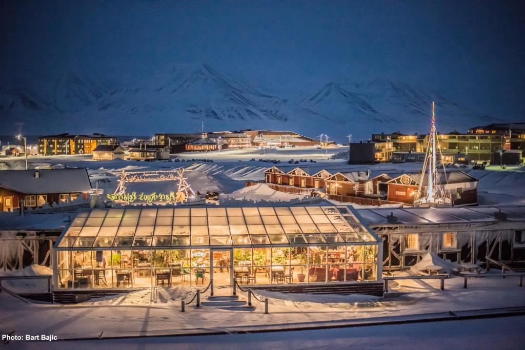 朗伊尔城玛丽安波拉里格酒店的一座大玻璃建筑,晚上在雪中