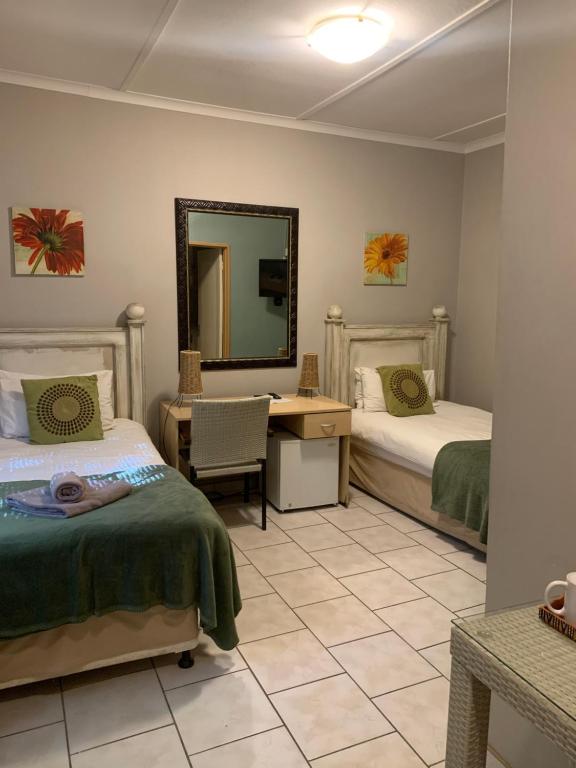 温特和克Hotel Pension Casa Africana的一间卧室配有两张床、一张桌子和一面镜子