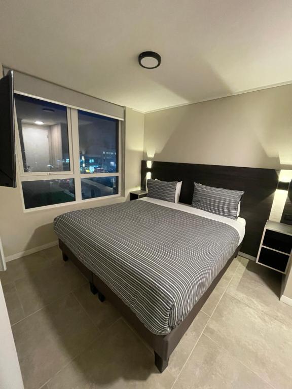 瓦尔迪维亚Epicentro Suites Apart Hotel - Valdivia的一间卧室设有一张大床和一个窗户。