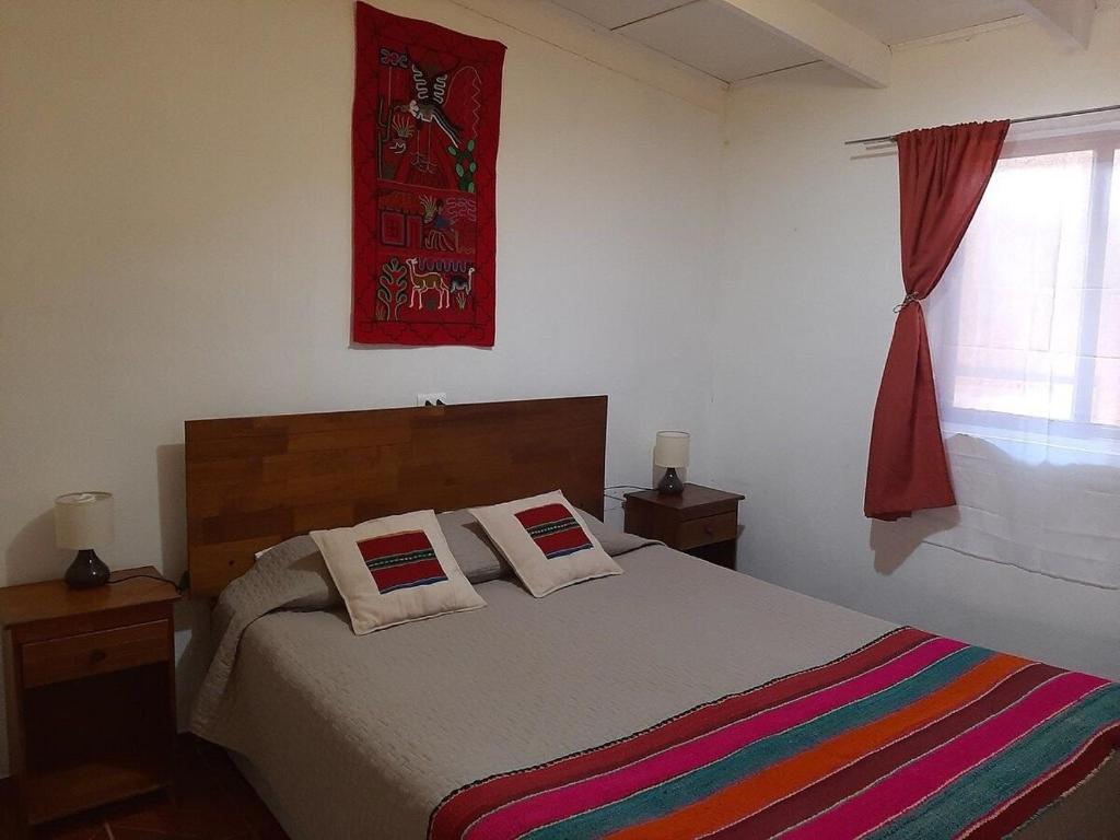 圣佩德罗·德·阿塔卡马Casa Sutar Los Pimientos的一间卧室配有一张带彩色毯子和窗户的床。
